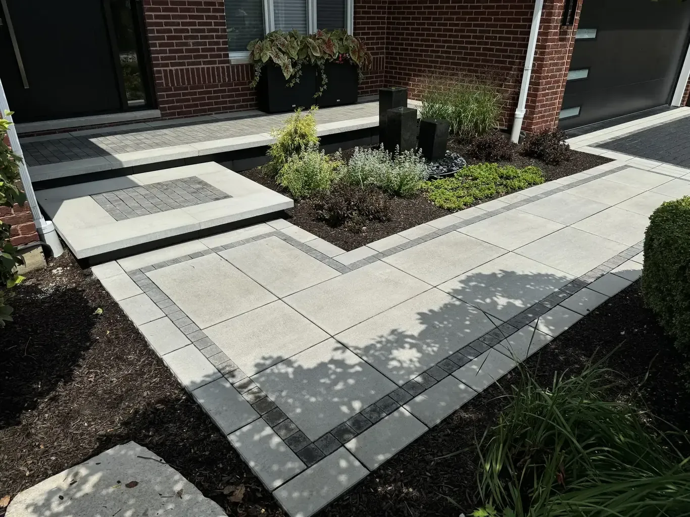 Modern large-format paver walkway with charcoal banding and planted beds by Rodak Landscaping in Frankfort