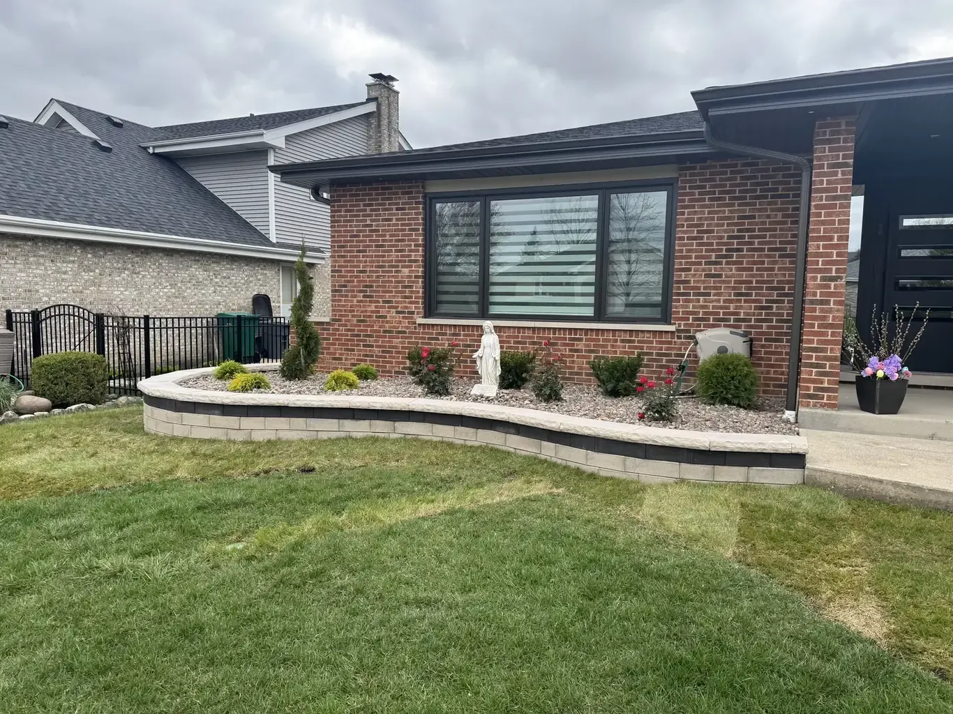 Curved two-tone block retaining wall with stone caps and planted bed by Rodak Landscaping in Orland Park