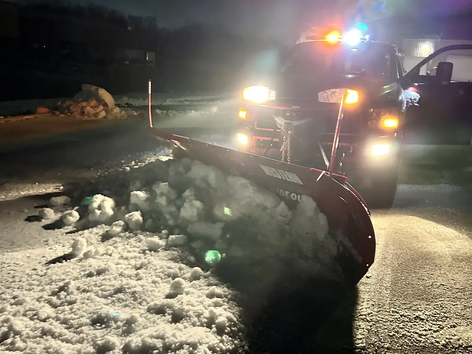 Commercial snow plow truck clearing a parking lot in winter for Rodak Landscaping