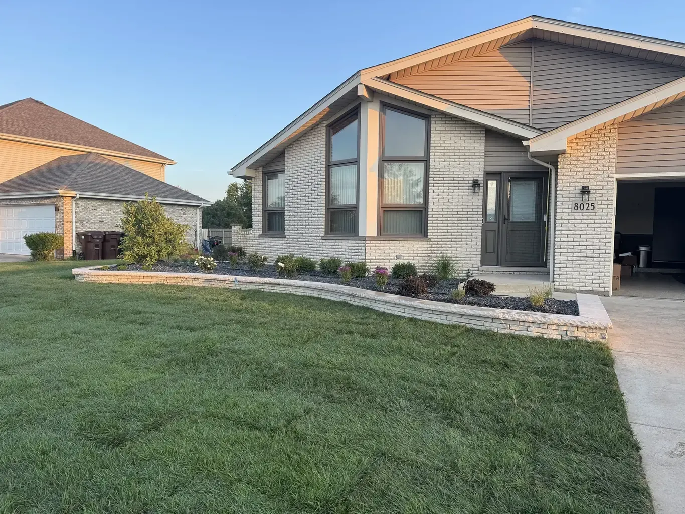 Curved stone retaining wall and fresh sod at golden hour, built by Rodak Landscaping in Tinley Park