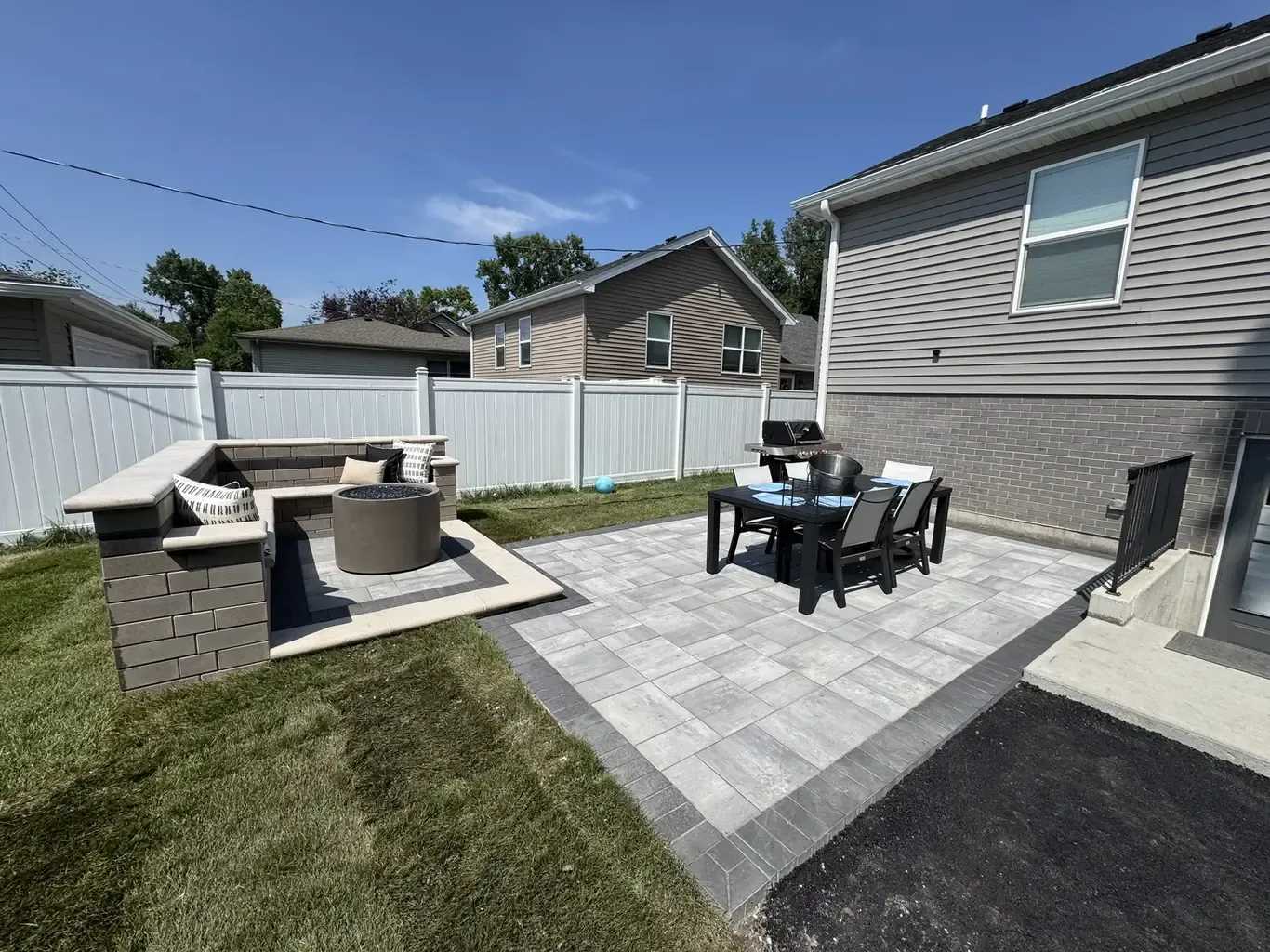 Multi-tone paver patio with sitting wall, fire table, and outdoor dining built by Rodak Landscaping in Tinley Park
